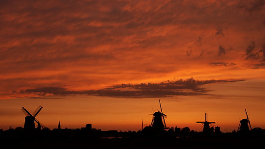 silhouette with 4 windmills under orange skies during sunset thumbnail