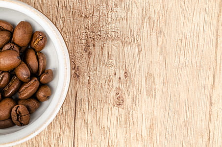 Coffee Beans on White Ceramic Bowl on Top of Brown Wooden Surface thumbnail