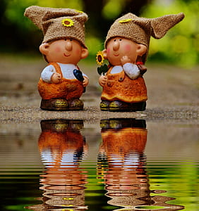 Girl and Boy Figurines Facing Each Other Near Body of Water thumbnail