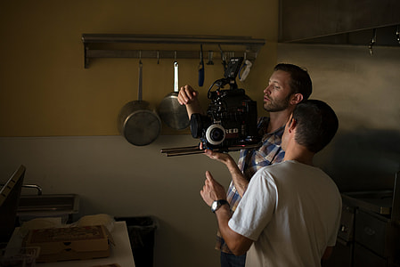 man holding video recorder beside man wearing white T shirt thumbnail