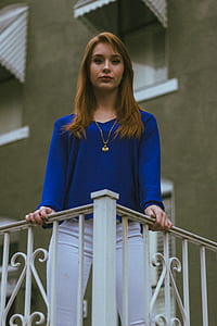 woman wearing blue v-neck long-sleeved shirt and white pants thumbnail