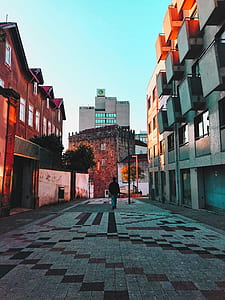 person in black jacket walking between buildings thumbnail