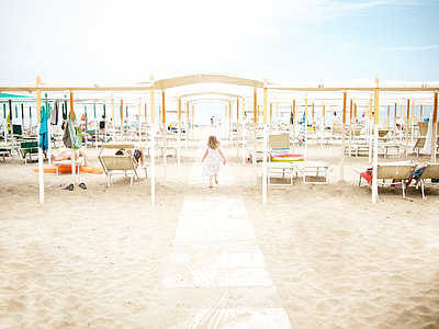 photo of girl in white dress walking under shade of white sheds thumbnail