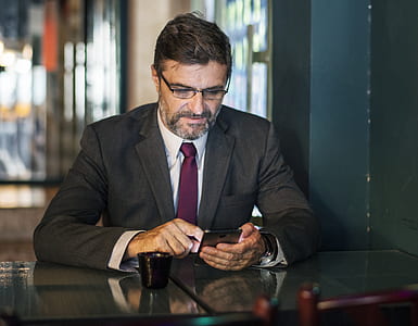 man in black suit jacket holding black smartphone thumbnail