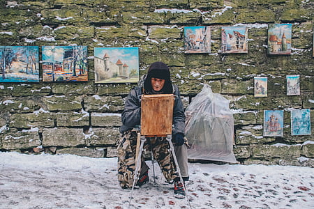 man in gray coat painting beside wall thumbnail