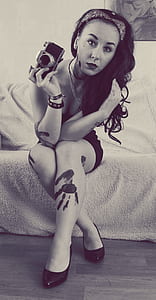 grayscale photo of woman holding a MILC while sitting on sofa thumbnail