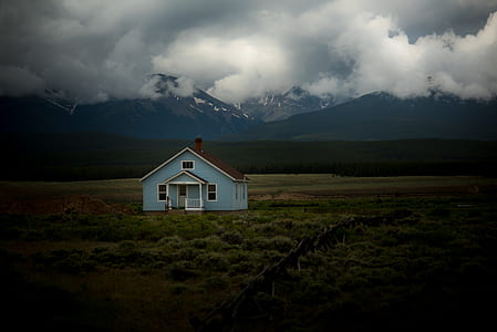 blue and brown wooden house in the middle of greenfield thumbnail