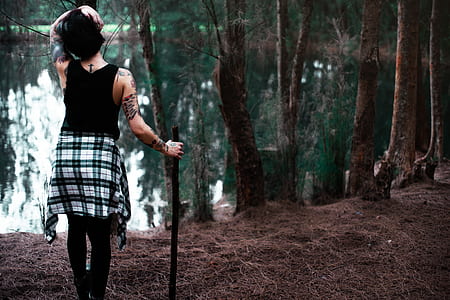 woman holding black stick standing near body of water thumbnail