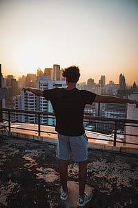 person raising both hand standing on roof building thumbnail