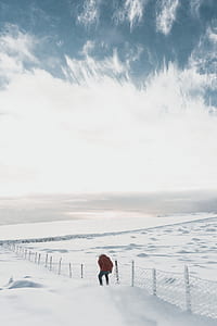 person beside fence on snow-covered field thumbnail