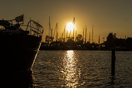 silhouette of boat floating on calm body of water thumbnail