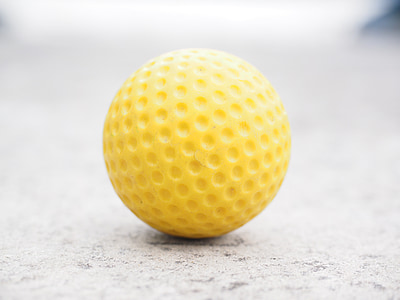 yellow golf ball on gray surface thumbnail