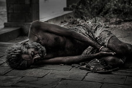 grayscale photo of man sleeping on floor near grass thumbnail