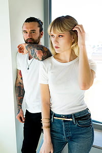 man and woman wearing white shirt standing beside wall thumbnail
