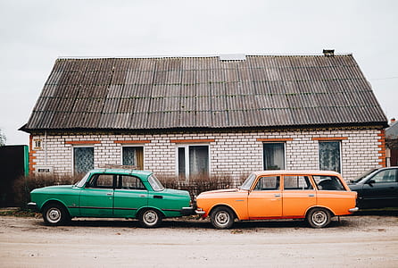 green sedan parking beside orange station wagon near house at daytime thumbnail