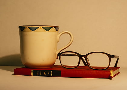 ceramic tea cup and wayfarer eyeglasses on top of red book thumbnail