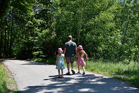 man holding to girls while walking on road thumbnail