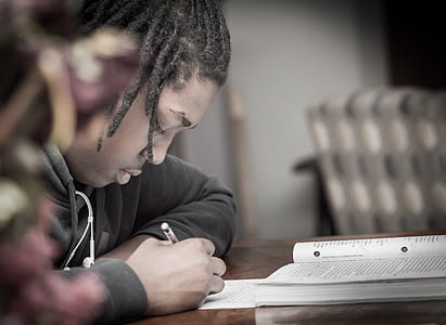man writing on paper sitting on front of table thumbnail