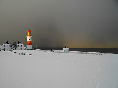 orange and white lighthouse on snow field during daytime thumbnail