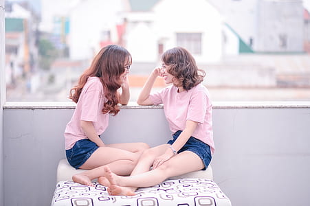 two woman wearing matching shirts and shorts sitting on cushion thumbnail