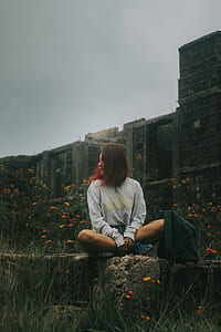 woman wearing grey long-sleeved shirt sitting on grey surface beside backpack thumbnail