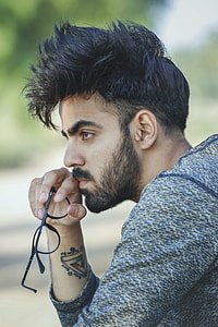 man wearing blue and gray sweater holding his eye glasses thumbnail