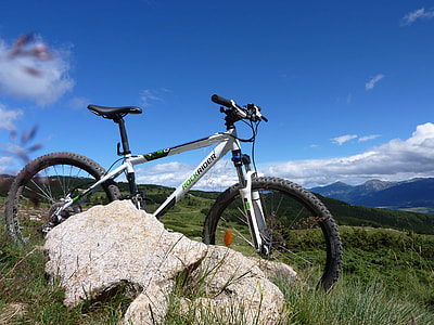 white and black hardtail bike parked near white rock thumbnail