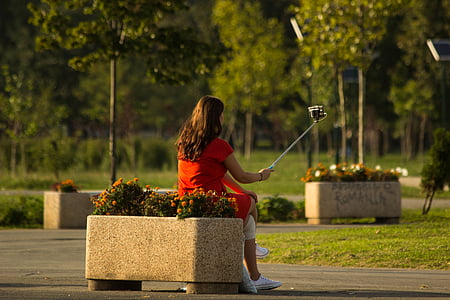 woman in red shirt sitting holding monopod thumbnail