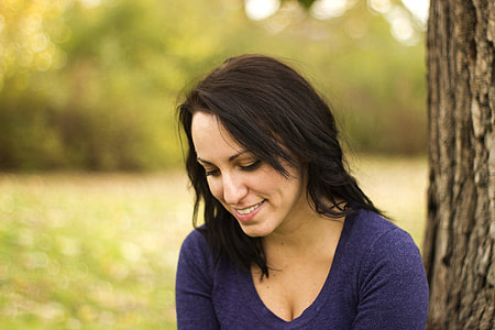 woman in blue shirt seats near tree at daytime thumbnail