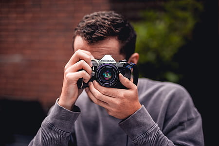 selective focus photography of man in blue sweater taking photo thumbnail
