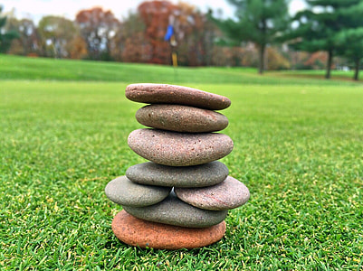 stacked stones placed on green grass field thumbnail