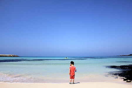 boy standing near body of water thumbnail