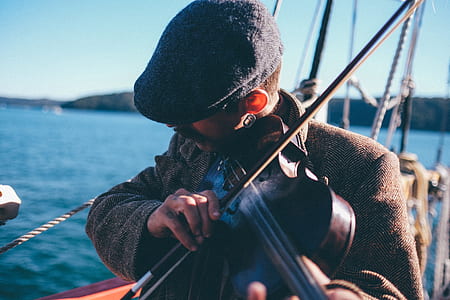 man playing violin near ocean thumbnail