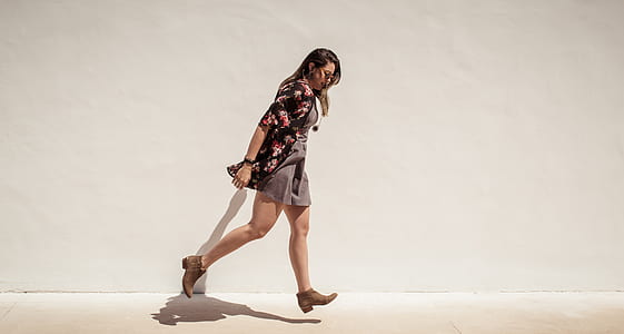 woman wearing floral dress walking beside concrete wall during daytime thumbnail