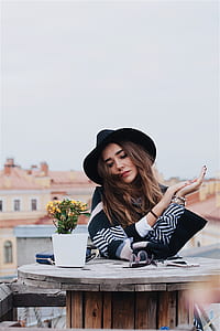 shallow focus photography of woman beside yellow flowers in white pot on brown spool thumbnail