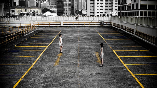 two women standing on empty parking area during daytime thumbnail
