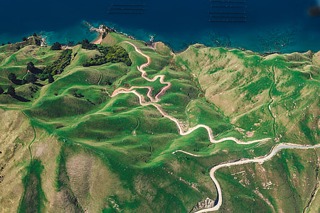 aerial photo of lush land formation with roads near sea thumbnail