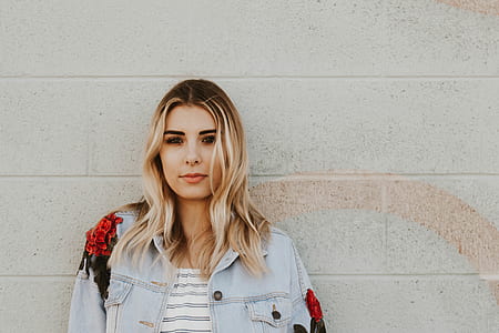 woman wearing blue denim button-up jacket leaning on wall thumbnail