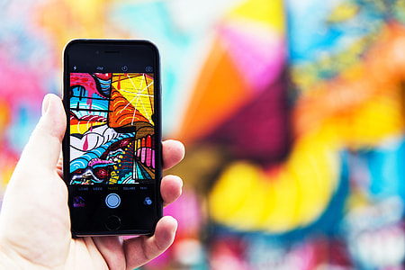 Man photographer capturing street art photo with his hand on iPhone mobile smartphone thumbnail