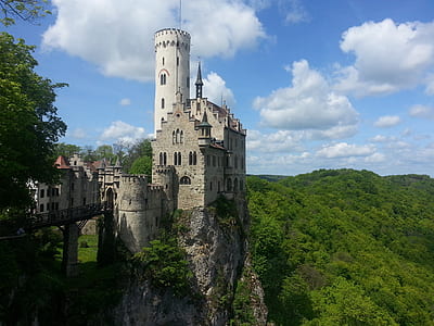 photography of gray stone castle on peak of mountain thumbnail