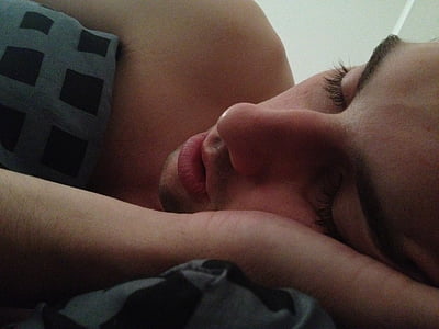 man topless sleeping on black and gray sheet inside room thumbnail