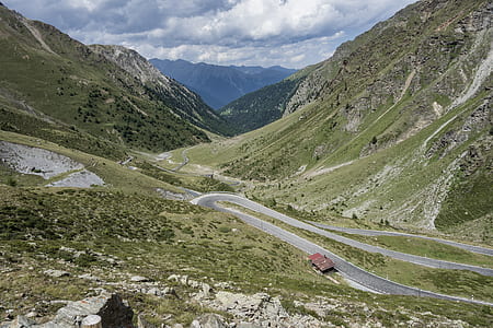 concrete road between mountain under blue and white sky thumbnail