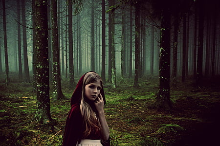 woman wearing red cloak standing in middle of forest thumbnail