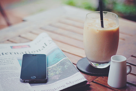 photography of space gray iPhone 5S on top of newspaper near drinking glass thumbnail