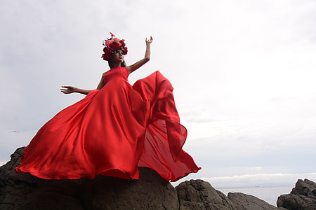 woman wearing red sleeveless dress posing for photo on top of rock formation thumbnail