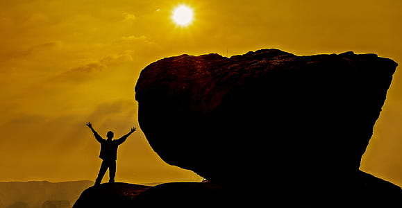 silhouette of person standing beside stone during daytime thumbnail