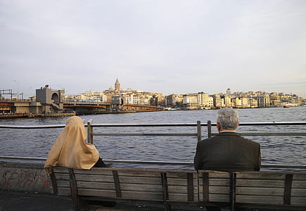 two person sitting on bench in front of body of water during daytim thumbnail