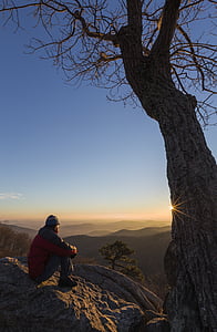 man sitting on rock watching sunrise thumbnail