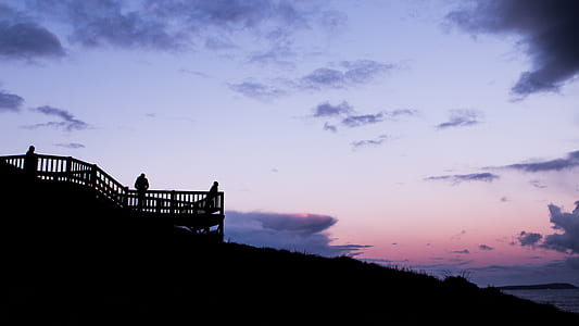 silhouette of three people standing on terrace during sunset thumbnail