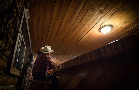 cowboy sitting inside brown wooden room thumbnail
